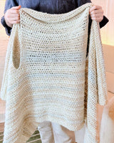Man holds up crochet blanket vest by armholes. thumbnail