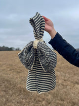 Close up of bow scarf held by hand of person off-camera. thumbnail