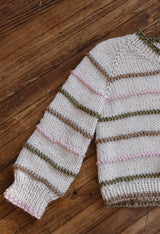 Sweater laid flat on dark wood floor, showing sleeve and right half of body. thumbnail