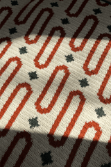 Close up of oval motifs in orange and stars in dark green on a cream background. thumbnail