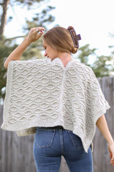 Back view of cabled poncho, showing split back neck and seam down the back. thumbnail