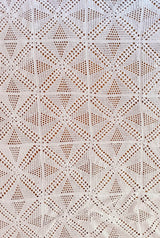Top down view of crochet coverlet made of individual blocks. The blocks combine to make a diamond pattern with openwork mesh. thumbnail