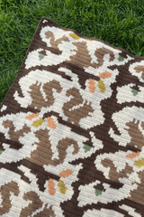 View of corner of crochet afghan, laid on grass. thumbnail