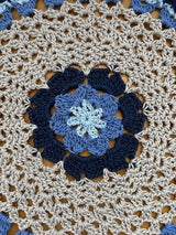 Close up of the center of doily. It is light blue in the middle, then medium blue, then dark blue, then a large section of cream/beige. thumbnail