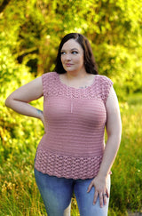 Front view of pale pink crochet top on a woman wearing jeans, standing in front of tall grass and green trees. The top has textured bands at the top and bottom, with a plain torso. thumbnail