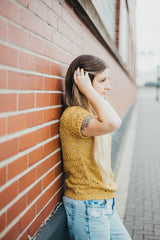 Side view of crochet lace top, worn by woman leaning against brick building. thumbnail