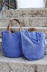 Two blue crochet bags sit on cement steps. One has leather shoulder straps and one has crochet straps in matching yarn. thumbnail