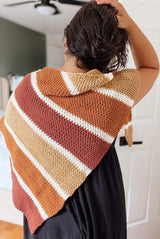 Back view of woman wearing striped shawl over a black dress. The shawl is an asymmetric triangle with larger stripes separated by smaller cream stripes. thumbnail