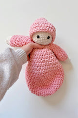 Crochet soft doll held under arms by person off camera. thumbnail