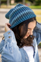 close-up of a person wearing a blue knit hat denim jacket and white shirt outdoors thumbnail