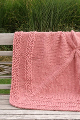 Coral pink blanket on wooden bench outdoors. thumbnail
