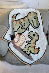 Close up of crochet afghan with t-rex family laying on couch. thumbnail