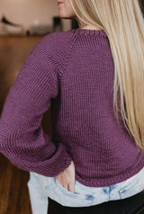 Back view of knit raglan sweater, worn by woman with long blonde hair. thumbnail