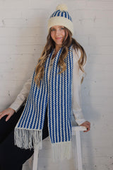 Model wears blue and white hat and matching scarf, unwrapped, indoors. thumbnail