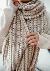 Close up of crochet scarf with lengthwise stripes in pale neutral shades.  thumbnail