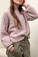 Side front view of pale pink crochet sweater, slightly oversized, worn with khaki pants.  thumbnail