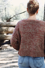 Back view of marled knit cardigan, worn with blue jeans and photographed outside. The cardigan body is cropped, with a wide ribbed hem and a ribbed neckband.  thumbnail