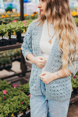 Front view of crochet cardigan with ribbed front bands. The woman wears it over a white tee shirt and jeans.  thumbnail