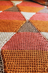 Extreme close up of Tunisian crochet texture on diamond motif, in rust, canyon red, taupe, and beige.  thumbnail