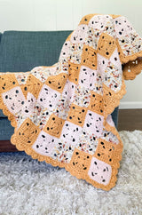 Patchwork baby blanket draped over the arm of a blue chair. The blanket is made of small squares in pale pink, mustard yellow, and a speckled multi-color.  thumbnail