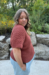 Side view of crochet tee, showing shoulder seam and short sleeve. Tee has an all-over textured pattern.  thumbnail