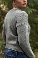 Side back view of grey sweater, showing  plain back and shoulder/sleeve seam. thumbnail