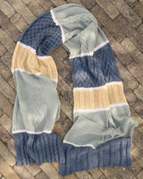 Top down view of knit scarf/shawl laid on brick patio. thumbnail