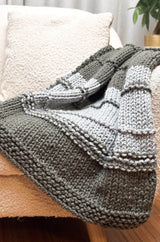 Close up of knit blanket showing garter borders and garter ridges across stockinette stitch main blanket. thumbnail