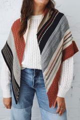 Cropped front view of large knit shawl worn draped over shoulders, over white top and jeans. thumbnail