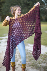 Woman holds lacy crochet wrap toward camera, showing open texture. thumbnail