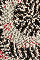 Close up of the center of a circular blanket. It's made in a super bulky weight chenille yarn in a multi color black/brown/beige/cream, and a beige worsted weight wool. thumbnail