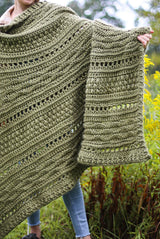 Close up of crochet afghan being held toward camera by woman. There are bands of different textures, ranging from 3" tall to 9" tall. thumbnail