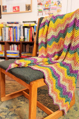 Crochet ripple throw draped over back of desk chair, in front of low bookcases. thumbnail