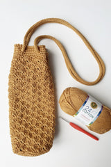 Flat lay of water bottle holder with long strap, crochet hook, and ball of yarn. thumbnail