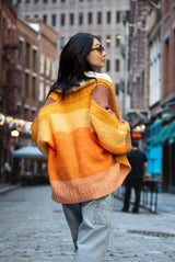 back of Woman wearing color changing cardigan on cobblestone street  thumbnail