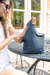 Woman holding a blue crochet bag on a table thumbnail