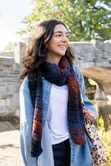 person wearing a multicolored crochet scarf denim jacket and white shirt outdoors thumbnail