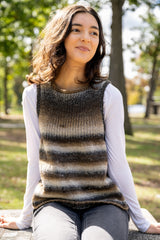 person wearing a brown and cream striped knit tank top and white shirt outdoors in a park thumbnail